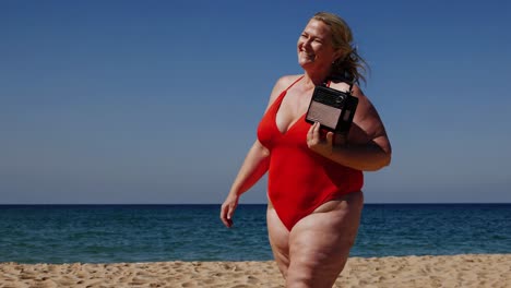 curvy woman radiating confidence, walking along sunny beach while listening to vintage portable radio, embodying body positivity and summer leisure