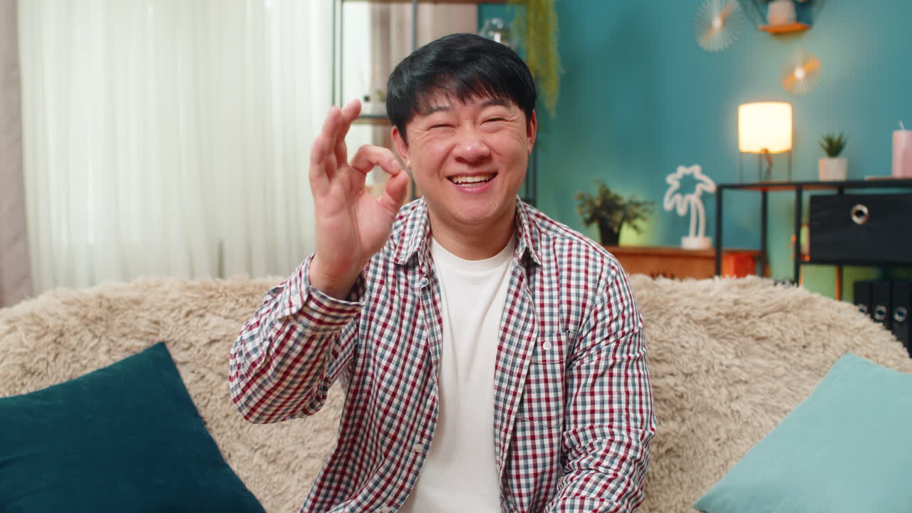 Asian cheerful man smiling at camera giving ok gesture positive assurance confirming everything fine