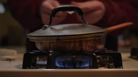 man-cooking-dinner-on-dirty-stovetop,-propane-burner-lit-in-trailer-park-home