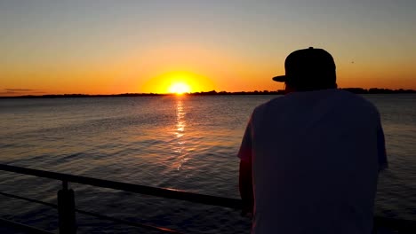 slow motion tracking shot of man looking at sunset river