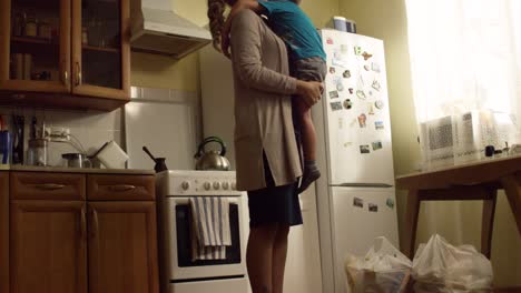 madre llevando a su hijo en la cocina
