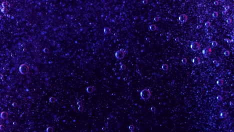 burbujas de color púrpura oscuro se elevan misteriosamente sobre un fondo negro mientras estas pequeñas esferas se elevan una cascada de burbujas más pequeñas caen en el fondo mostrando las corrientes creadas por las burbujas más grandes