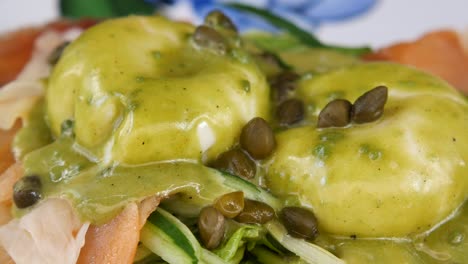 close-up of poached eggs with green sauce and capers