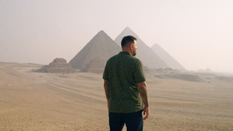 a man admiring the giza plateau, with the pyramids in view at sunrise near cairo, egypt - static shot