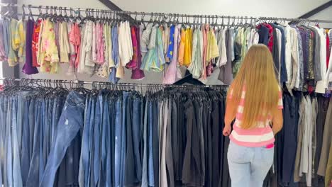 rows of secondhand clothes hang on hangers a woman buys used clothes rows of secondhand clothes hang on hangers a woman buys used clothes
