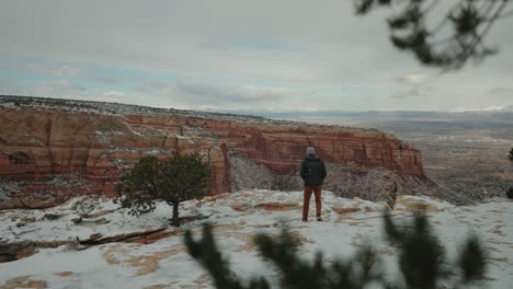 a man walking in the snowy canyon while the storm is brewing overhead