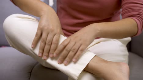 woman sitting on the sofa at home performing self massage