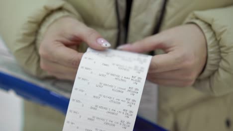 el comprador tiene un recibo de compra en sus manos, comprueba las compras y los precios