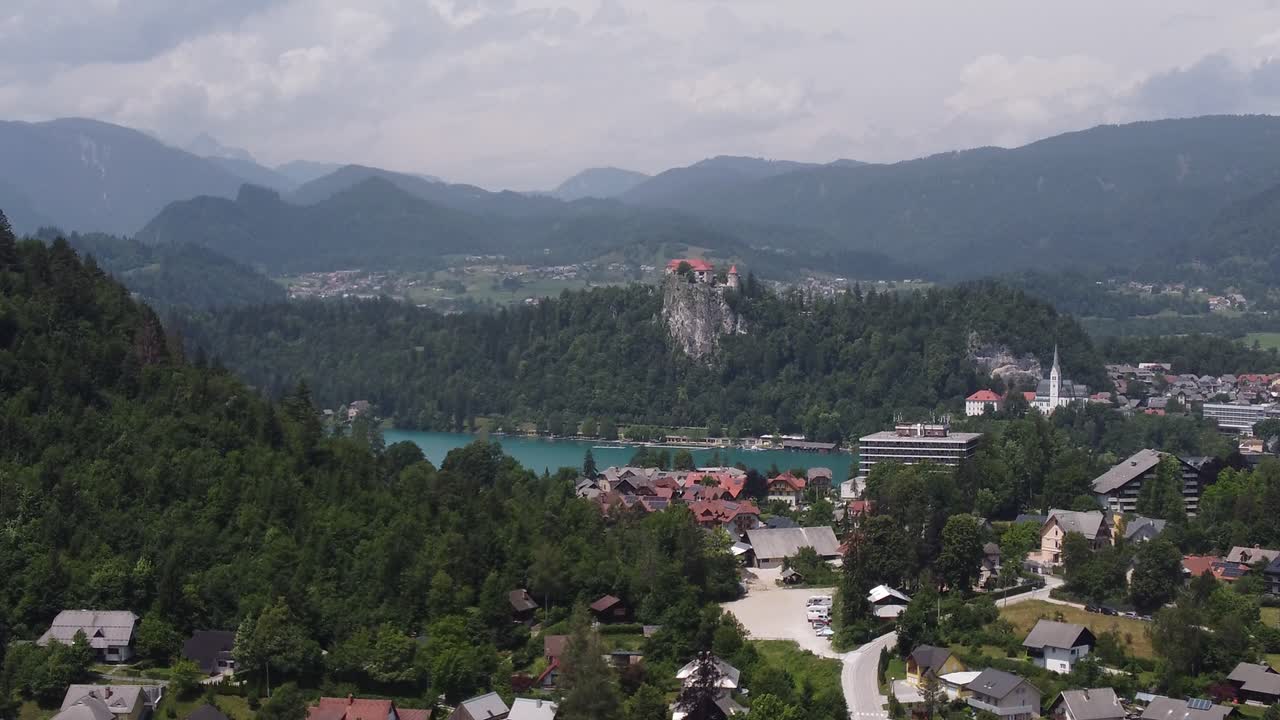 Ripresa ascendente con drone che mostra la città di Bled con il famoso lago e il castello sulla collina sullo sfondo.