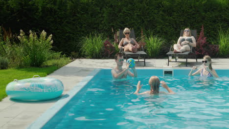 a group of friends play ball in the pool and relax on sun loungers. have fun in the backyard of the house