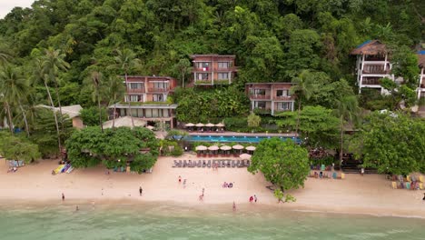 rising drone reveals tourists enjoying day at beach and luxury cliffside villas, el nido