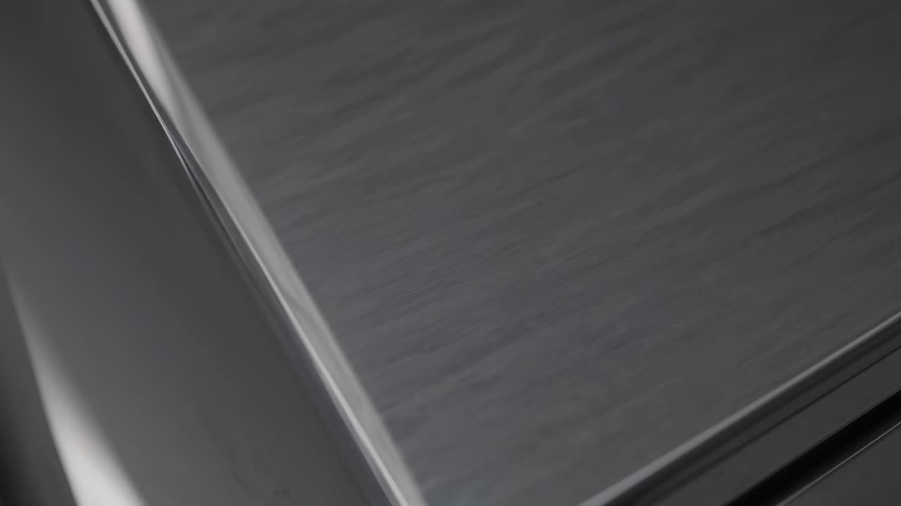Primo piano, angolazione dall'alto di una superficie texturizzata, che ricorda un metallo spazzolato o un tessuto