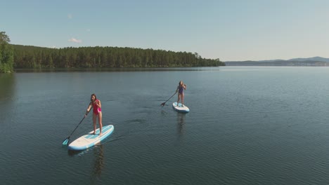 Aerial-View-Of-Two-Girls-In-Swimsuit-Doing-Paddle-Surfing-In-The-Sea