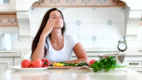 retrato de una ama de casa cansada con dolor de cabeza tocando la cabeza haciendo masaje circular mientras cocina