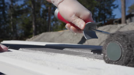 woman with plastic gloves painting planks with a paint roller brush