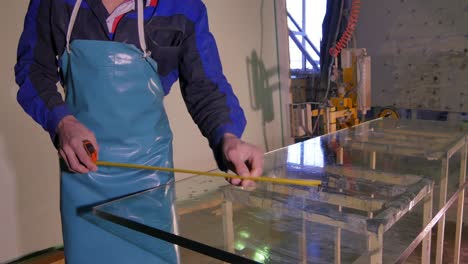 worker measuring glass at a fabrication facility