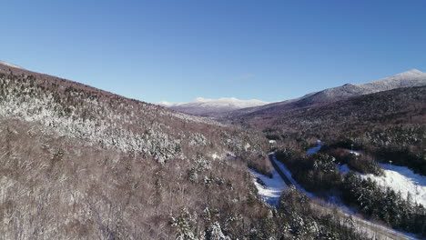 rising, pulling back and panning drone shot of winter mountain valley with river and road