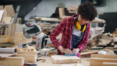 woman woodworker sanding wood in workshop