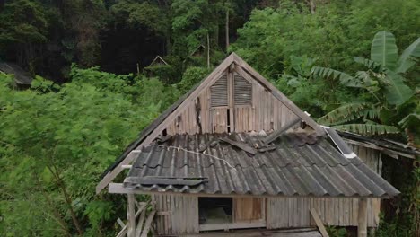 dolly shot droneflyes closely over old style wooden thai bungalow that is now derelict and unused due to the effects of the pandemic on travel and tourism