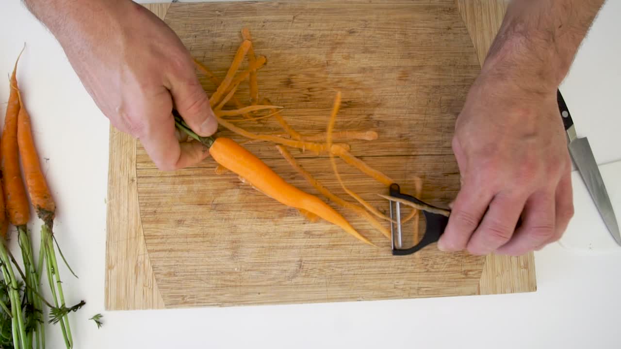 Overhead of chef peeling organic carrots