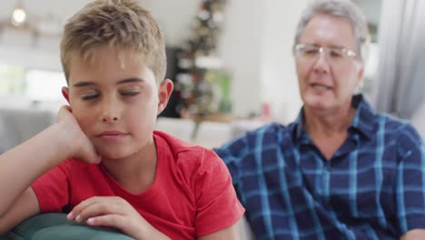 abuelo y nieto caucásicos sentados en el sofá y hablando, cámara lenta