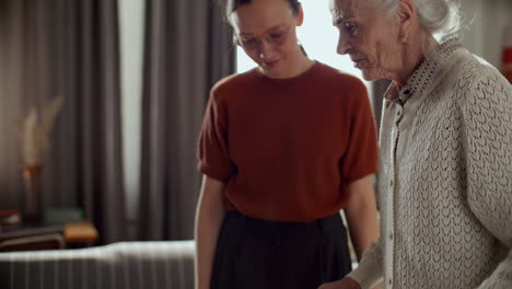 elderly woman walking with walker assisted by granddaughter at home