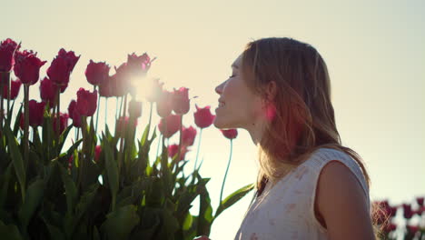 Closeup-woman-face-profile-smelling-flowers-in-sun-reflecction-bright-sunny-day.