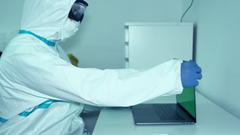 physician wearing protective bunny suit starts working on medical research during covid19 pandemic - medium shot