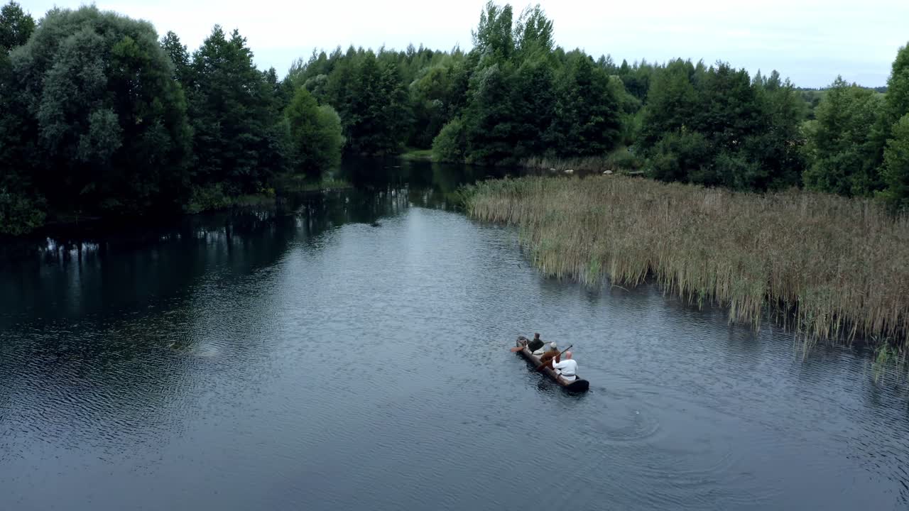 Three men boating in wooden dugot on lake