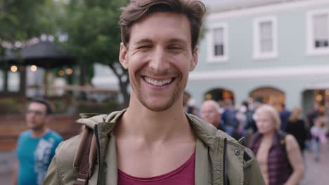 portrait of handsome young man looking laughing cheerful at camera urban background