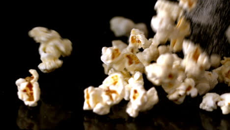 popcorn and salt pouring onto black surface