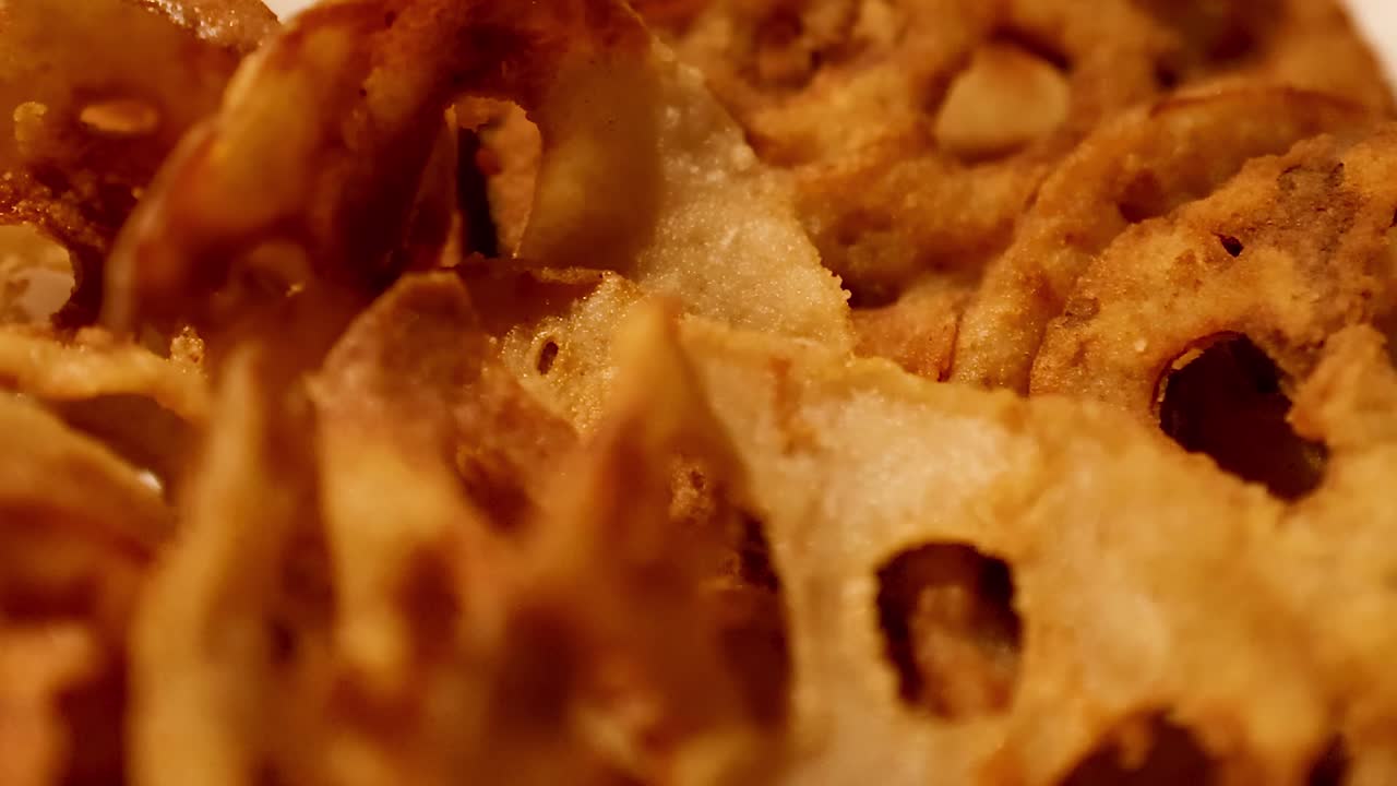 A detailed view of golden brown lotus root chips arranged in a basket, showcasing their crispy texture.