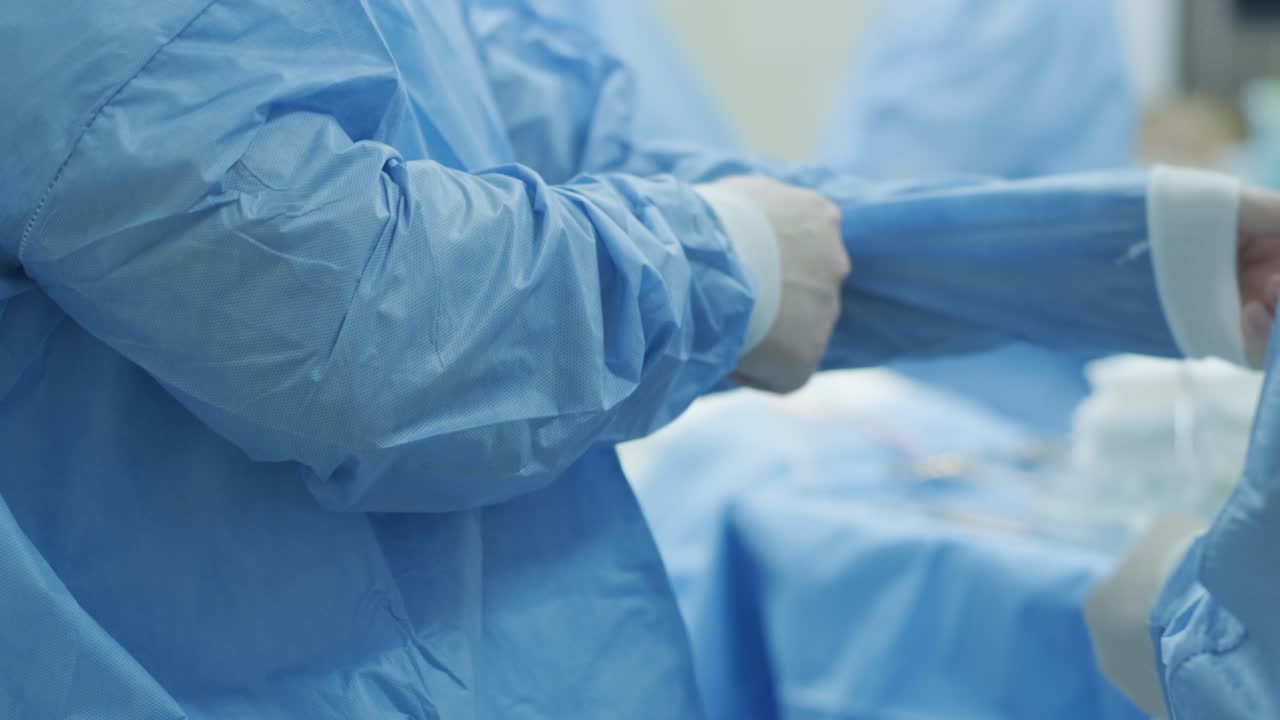 Il chirurgo si prepara per l'operazione, allaccia il camice sterile nella moderna sala operatoria.