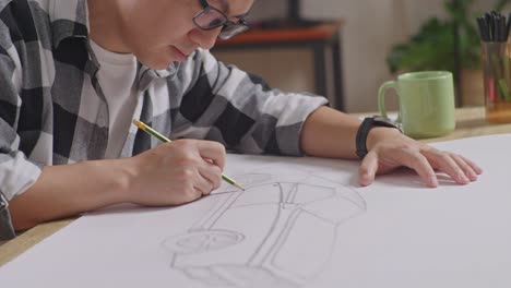 close up of asian male yawning while working on a car design sketch on table in the studio