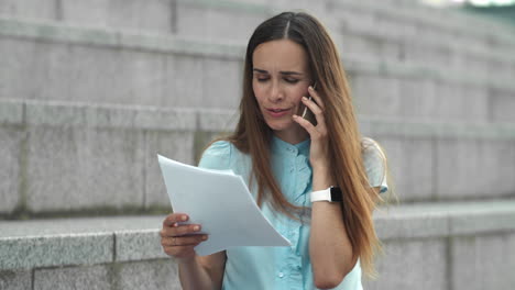 Mujer-De-Negocios-Hablando-Por-Teléfono-Inteligente-En-La-Calle.-Ejecutivo-Mirando-Documentos