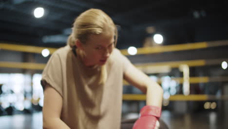 exhausted female boxer wiping sweat in sport club. fitness woman sitting at gym