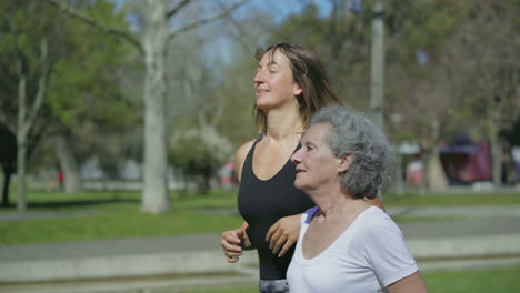 Vista-Lateral-De-Dos-Mujeres-Corriendo-En-El-Parque,-Hablando-Y-Sonriendo.