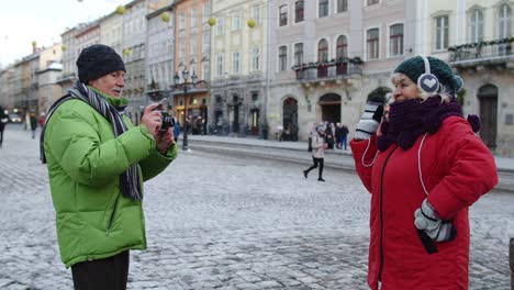 Pareja-De-Ancianos-Turistas-Abuela-Abuelo-Tomando-Fotografías-Con-Cámara-Retro-En-La-Ciudad-De-Invierno