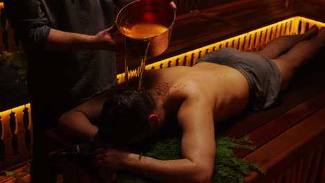 man receiving traditional sauna oil treatment