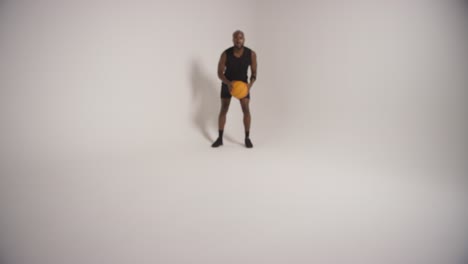 full length studio shot of male basketball player dribbling and bouncing ball against white background 2