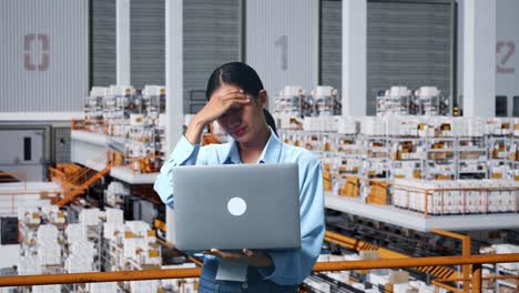 an asian business woman not satisfied and shakes her head while using laptop computer in the warehouse