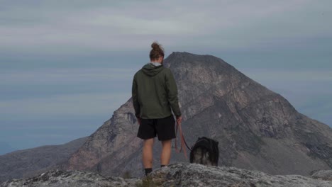 excursionista con perro de mascota en la correa de pie en la colina de salberget en noruega