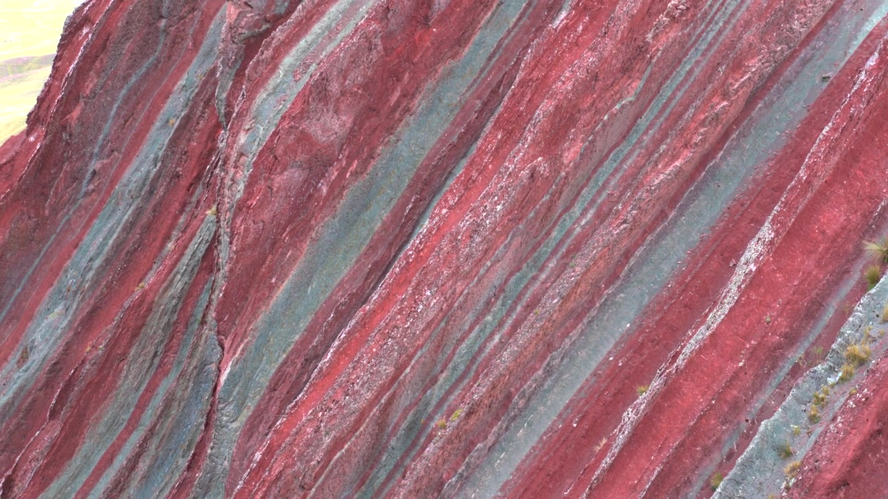 Close-up shot of the vivid red and grey mineral strata on Pallay Punchu mountain near Layo, Cusco, Peru.