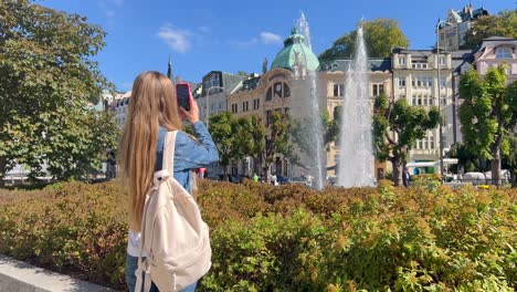 girl taking a photo of a fountain in a european city
