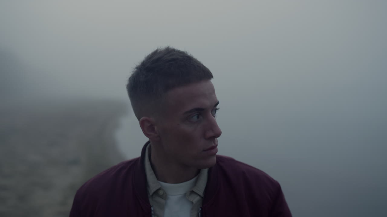 Depressed man looking ocean horizon in morning mist. Guy walking on sea shore
