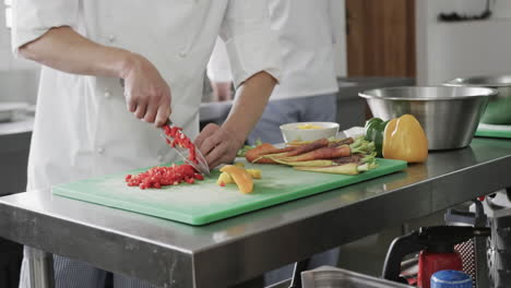 chef caucásico cortando verduras en la cocina, en cámara lenta