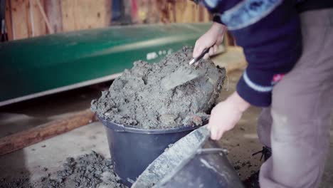 The-Man-is-Transferring-Cement-Into-a-Bucket-For-Use-in-the-Construction-of-a-DIY-Hot-Tub---Close-Up