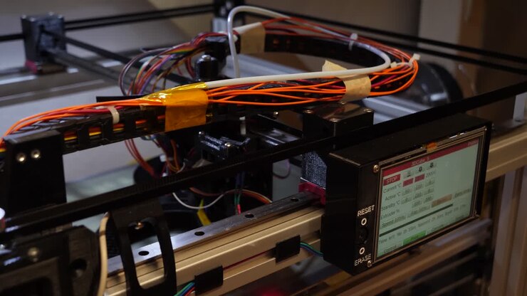 Dolly left showing the moving parts of a 3D printer with a lot of cables