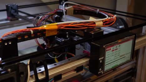 dolly a la izquierda mostrando las partes móviles de una impresora 3d con muchos cables