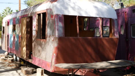 slide right revealing a dirty old damaged vintage metal travel trailer in the middle of a restoration and rebuild process